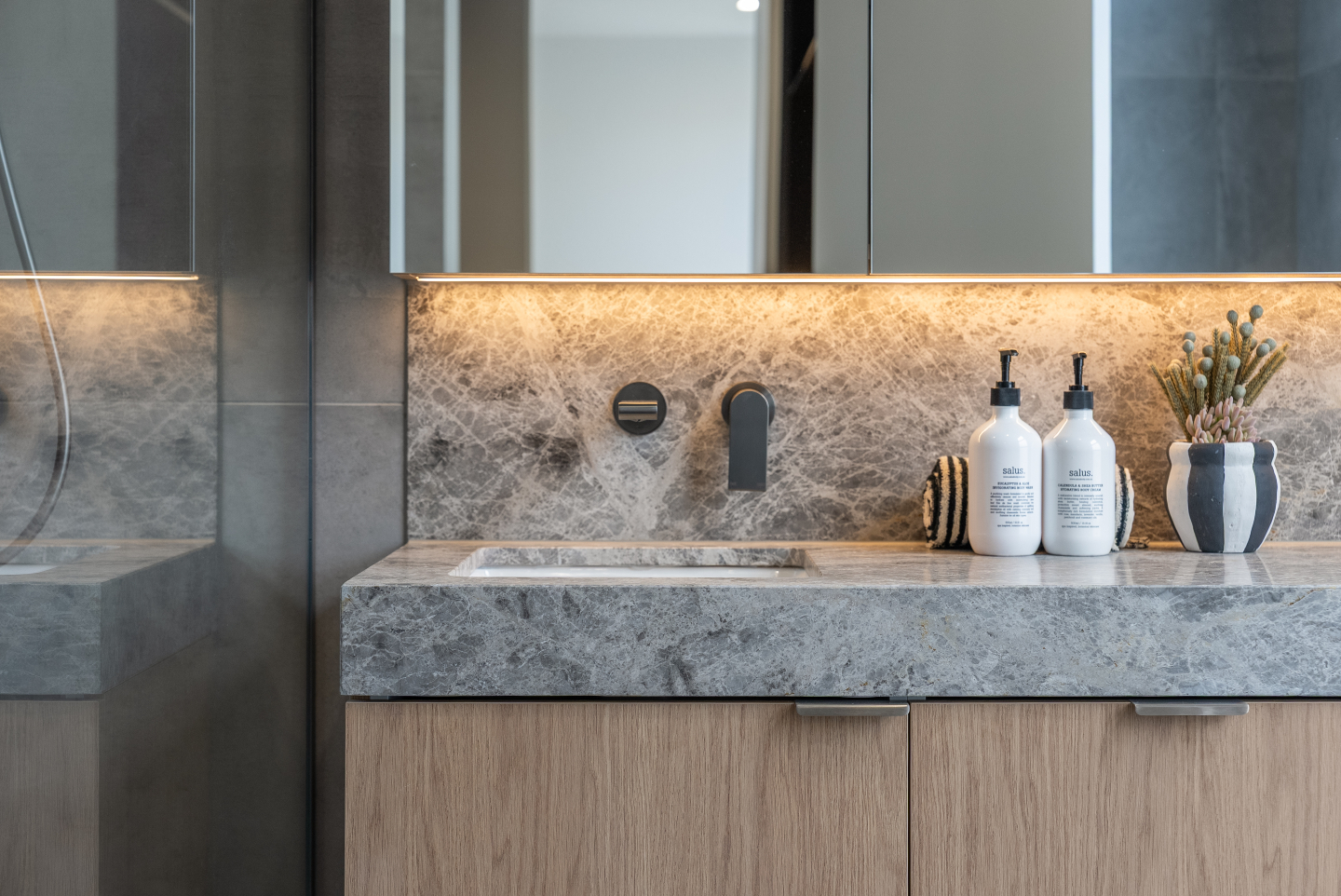 A closer look at the bathroom finishes at Venus Street, Caulfield. Natural stone, warm lighting and clean, understated detailing c…